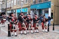 Several men dressed with typical Scottish kilts playing the highland bagpipes through the streets of Inverness, Highlands.