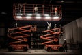 Several men in work attire standing on top of a red scissor lift at a construction site, Workers install lighting fixture in a hug