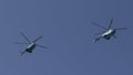 Several military helicopters fly side by side against the blue sky