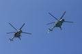 Several military helicopters fly side by side against the blue sky