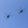 Several military helicopters fly side by side against the blue sky