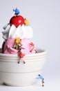 Miniature, toy climbers ascend a small bowl of ice cream.