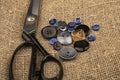 Several multi-colored buttons of different sizes and large vintage sartorial scissors against a background of coarse-textured Royalty Free Stock Photo