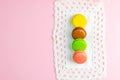 Several multicolored macaroons pastel colors on a white napkin on pink background