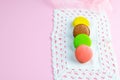 Several multicolored macaroons pastel colors on a white napkin on pink background