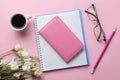 Several notebooks a cup of coffee and flowers on a bright pink background. top view. office tools Royalty Free Stock Photo