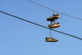 Several tennis shoes on power lines in front of a clear blue sky. Royalty Free Stock Photo