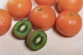 Several orange tangerines. Kiwi fruit cut in half. Juicy green flesh is visible. Lie on a beige surface Royalty Free Stock Photo