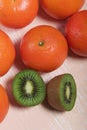 Several orange tangerines. Kiwi fruit cut in half. Juicy green flesh is visible. Lie on a beige surface Royalty Free Stock Photo