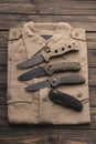 Several penknives on a folded shirt. Folding pocket knives. Dark wooden back