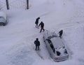 Several people dig up a stuck car in the snow in the Parking lot of the snow