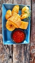 several pieces of fried sweet potato and chili sauce in a small bowl on a blue square plate Royalty Free Stock Photo