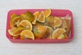 Several pieces of local Indonesian citrus fruit, in a pink rectangular plastic container.