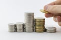 Several Piles of coins with a hand placing one Royalty Free Stock Photo