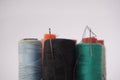 Several piles of sewing thread spools of various colors isolated on a white background and also with small sewing needles Royalty Free Stock Photo