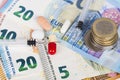 Several pills and syringes on euro banknotes, with coins.