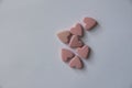 Several pink heart-shaped Vitamins lie on a white background