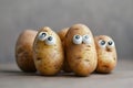 Several potatos with glued googly eyes, grey background