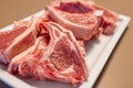 Several raw lamb chops on white plate show marbled pink meat and visible fat ready for cooking Royalty Free Stock Photo