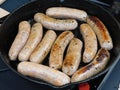 Several raw sausages being cooked barbecued over an induction cooker