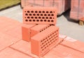 Several red perforated bricks against of pallets of bricks closeup