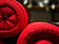 Several red rolls of knitted fabric. Woven factory or warehouse
