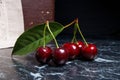 Several red sweet cherries and big green leaf on dark marble background.. Royalty Free Stock Photo