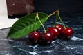 Several red sweet cherries and big green leaf on dark marble background.. Royalty Free Stock Photo