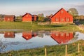 Several red wooden houses reflected in pond