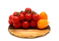 Several red and yellow ripe tomatoes on a cutting board on a light background.