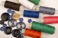 Several reels of multicolored sewing thread and multicolored buttons of different sizes on a white background. Close up Royalty Free Stock Photo