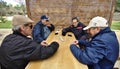 Several retirees play the outdoor game of dominoes at a table in the