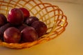 Several ripe plum lie in a braided tray