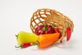 Several ripe sweet and hot peppers in a straw basket on a white Royalty Free Stock Photo