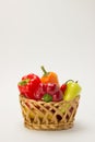 Several ripe sweet and hot peppers in a straw basket on a white Royalty Free Stock Photo