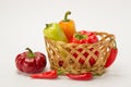 Several ripe sweet and hot peppers in a straw basket on a white Royalty Free Stock Photo
