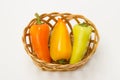 Several ripe sweet and hot peppers in a straw basket on a white Royalty Free Stock Photo