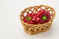 Several ripe sweet and hot peppers in a straw basket on a white Royalty Free Stock Photo