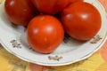 Several ripe tomatoes are on a plate.