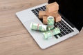 Several rolls of euro bills and a model of a courier box are placed on the opened laptop keyboard Royalty Free Stock Photo