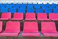 Several rows of plastic seats in red, blue and white colors mounted on brown-painted wooden platforms on podium of village stadium Royalty Free Stock Photo