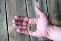 Several Russian metal rubles lie in a man`s hand over a wooden t