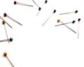 Several sewing pins with colored beads lie on a white isolated background. Place for text. View from above.