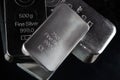 Several silver bars of various weights on a dark