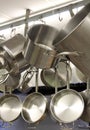 Several sizes and shapes of pots and pans hanging from hooks in kitchen Royalty Free Stock Photo