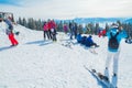 Several skiers rest on the top of the mountain. A group of people in ski suits sitting on the snow s makes a selfie