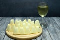 Several slices of ripe melon, cut into small pieces, lie on a cutting board. There is a glass of white wine nearby. Wooden table Royalty Free Stock Photo