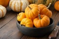 Several small pumpkins in a wooden bowl on kitchen table