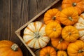 Several small pumpkins in a wooden crate on a kitchen table