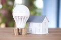 Several stacks of euro coins fixed to light bulb and a house model Royalty Free Stock Photo